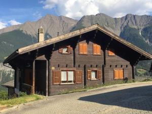una pequeña casa de madera con montañas en el fondo en Holiday Home Ferienhaus Godo by Interhome en Mörel