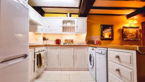 a kitchen with white appliances and yellow walls at River Nene Cottages in Water Newton