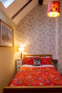 a bedroom with a bed with a red comforter at River Nene Cottages in Water Newton