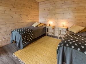 two beds in a room with wooden walls at Holiday Home Villa kurki by Interhome in Torvoila