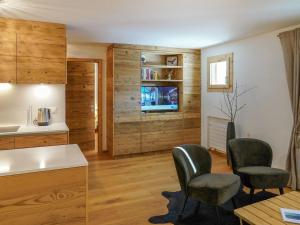 uma cozinha com paredes de madeira, 2 cadeiras e uma mesa em Apartment Chesa Palüdin 5 - Celerina by Interhome em Celerina