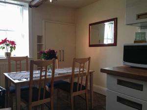 a kitchen with a table with chairs and a television at 12 Rattle Row in Holmfirth