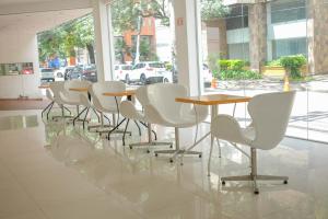 una fila de sillas y mesas blancas en un edificio en Hotel Senses Equipetrol en Santa Cruz de la Sierra