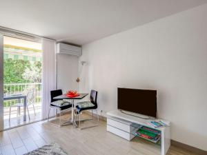 a living room with a television and a table with chairs at Studio Le Mexico-8 by Interhome in Saint-Raphaël