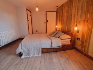 1 dormitorio con 1 cama con pared de madera en Pass the Keys Charming 19th century country cottage for 2 guests, en Exeter