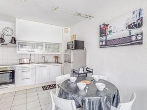 a kitchen with a table and chairs and a refrigerator at Apartment Le Cesarée-5 by Interhome in Fréjus