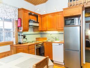 eine Küche mit Holzschränken und einem Kühlschrank aus Edelstahl in der Unterkunft Holiday Home Fore camp by Interhome in Tahkovuori