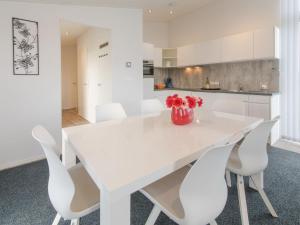 a white dining room table with white chairs and a vase of flowers at Holiday Home Ruisweg 38 by Interhome in Wemeldinge +13 photos