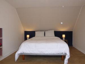 a bedroom with a large white bed with two lamps at penty breton in Pouldreuzic