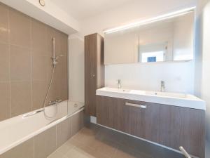 ein Badezimmer mit einem Waschbecken, einer Badewanne und einem Spiegel in der Unterkunft Apartment Residentie Odyssea I by Interhome in Bredene
