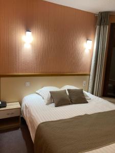 Le Malzieu-VilleにあるLogis Hotel Restaurant des Voyageursのベッドルーム1室(大型ベッド1台、枕2つ付)