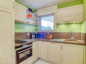 d'une cuisine avec des placards blancs, des murs verts et une fenêtre. dans l'établissement Apartment Bibi Beaurivage by Interhome, à Biarritz