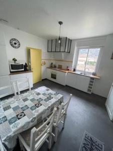 une cuisine avec une table, des chaises et une horloge dans l'établissement Appartement Tarascon sur Ariège, à Tarascon-sur-Ariège