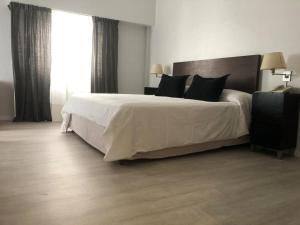 a bedroom with a large white bed and a window at Hotel La Perla in Buenos Aires