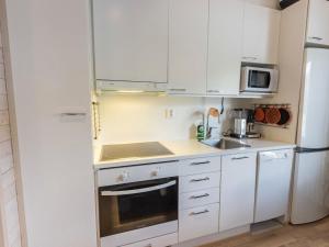 a small kitchen with white cabinets and a refrigerator at Holiday Home Levin stara a03 by Interhome in Levi