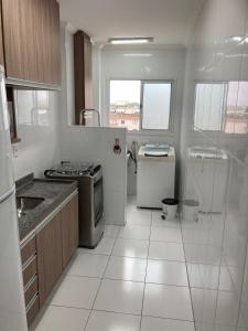 a white kitchen with a stove and a refrigerator at Pé na areia Fábio e Silvia in Praia Grande