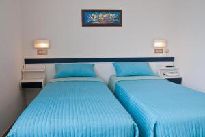 two twin beds in a room with blue sheets at Albergo La Rosetta in Chianciano Terme