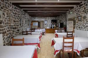 a restaurant with white tables and chairs and a stone wall at Le Bilboquet in Le Puy-en-Velay