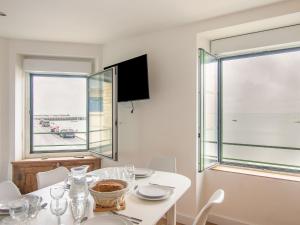 a white dining room with a table and a window at Apartment Le point du jour 1 by Interhome in Cancale