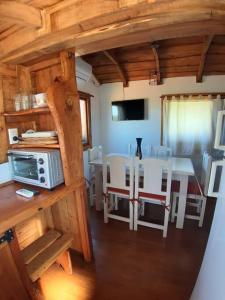 a kitchen and dining room with a table and a microwave at La Cabaña de Sofi in Tandil