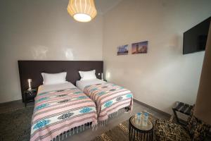 - une chambre avec 2 lits et une télévision dans l'établissement Riad Shanima SPA Marrakech, à Marrakech