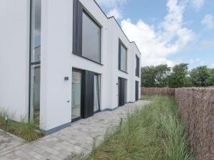 a white house with black windows and a sidewalk at Holiday Home Bredunepark-2 by Interhome in Bredene