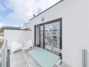a white house with a balcony with a bed and chairs at Holiday Home Bredunepark-2 by Interhome in Bredene