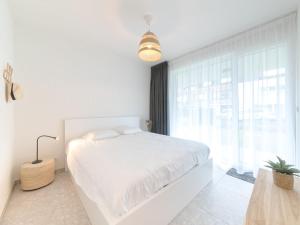 a white bedroom with a bed and a large window at Holiday Home Bredunepark-2 by Interhome in Bredene