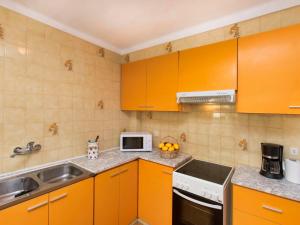 cocina con armarios de color naranja, fregadero y microondas en Apartment Moré III by Interhome en Llança