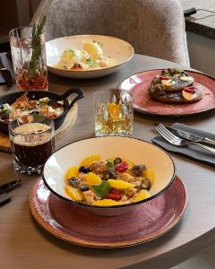 ヴィリニュスにあるCALVARY Hotel & Restaurant Vilniusの食べ物の皿が3枚置かれたテーブル