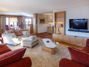uma sala de estar com uma televisão e um sofá e cadeiras em Apartment Pré Vert 3 by Interhome em Villars-sur-Ollon