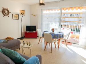 a living room with a table and chairs and a television at Apartment Les Cyclades-9 by Interhome in Le Lavandou