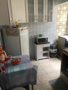 a kitchen with a refrigerator and a table with fruit on it at Apto Praia Grande - 50 metros da praia in Sao Paulo