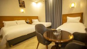 a hotel room with two beds and a table at Hotel de paris in Casablanca