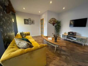 a living room with a yellow couch and a table at Lower Flat, Nicolson House. in Portree