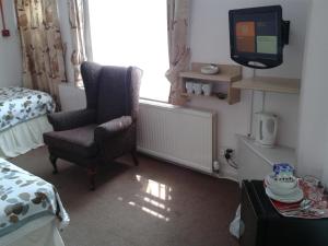 a bedroom with a chair and a tv and a bed at Overnight Stays Stockport in Stockport