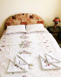 un letto con lenzuola bianche e fiori sopra di Apartman Djina a Vrnjačka Banja