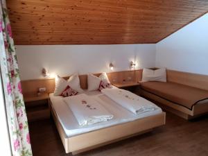 a bedroom with a white bed with a wooden ceiling at Pension & Appartament Anna in Predoi