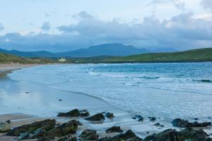 a beach with rocks and the ocean on a cloudy day at Balnakeil House in Balnakeil