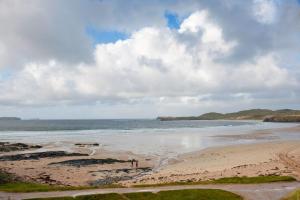 two people standing on a beach near the ocean at Balnakeil House in Balnakeil