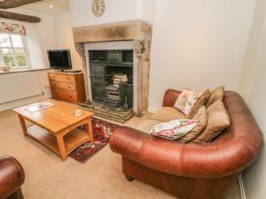 a living room with a leather couch and a fireplace at Fleshbeck Cottage in Barbon