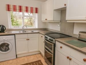 a kitchen with white cabinets and a dishwasher at Fleshbeck Cottage in Barbon