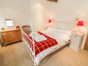 a bedroom with a white bed with a red blanket at Fleshbeck Cottage in Barbon