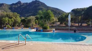 a swimming pool with a mountain in the background at New Camping Coccorrocci in Marina di Gairo