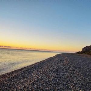 a rocky beach with the sun setting over the water at New Camping Coccorrocci in Marina di Gairo