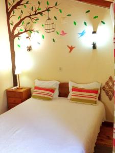una camera da letto con un letto con un albero e uccelli sul muro di Casas do Cruzeiro a Sabugueiro