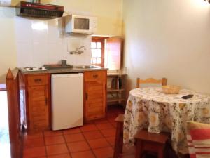 cocina con mesa y nevera blanca en Casas do Cruzeiro, en Sabugueiro