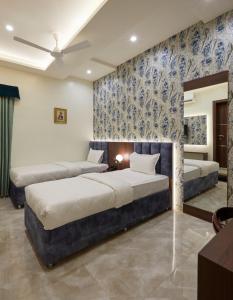 two beds in a bedroom with blue and white wallpaper at Hotel Rose Gold in Ahmadnagar