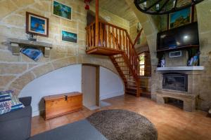 uma sala de estar com uma escada e uma lareira em Ta Rummiena Farmhouse em Xewkija