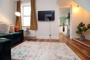 a living room with a green couch and a flat screen tv at The Nook At Bath by MGroupSA in Bath